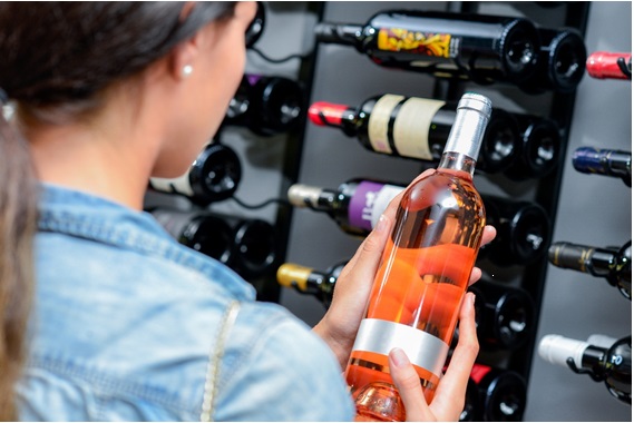 ワインセラーの前でロゼワインのボトルを手に取っている画像