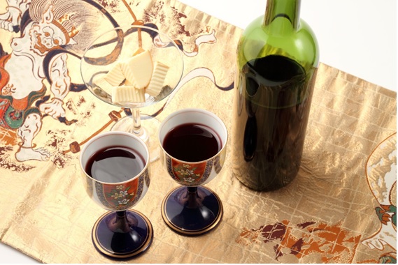 風神が描かれた敷物の上に赤ワインがある画像