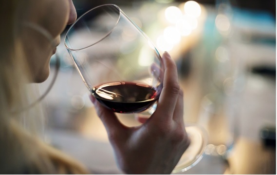 女性が赤ワインのグラスを傾けている画像