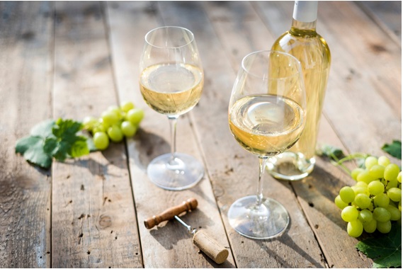 屋外の木製の机の上に白ワインのグラスが並んでいる画像